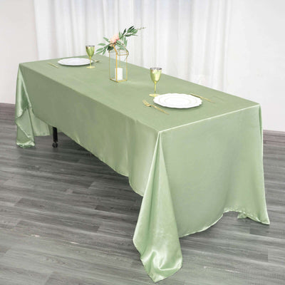 Elegant green tablecloth draped over a dining table with table settings.