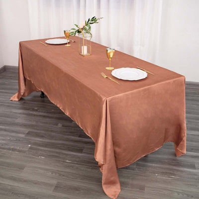 Rust-colored tablecloth draping elegantly over a dining table set for a meal.