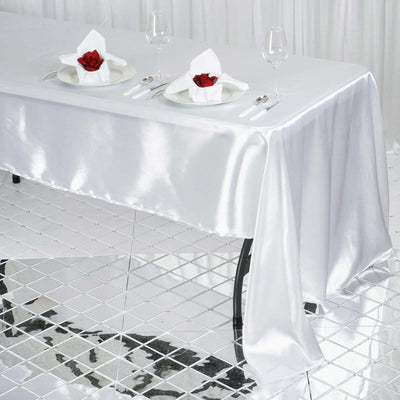 Elegant white satin tablecloth with rose centerpiece and dining setup.