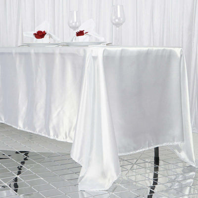 Elegant white satin tablecloth draped on a modern table with decorative elements.