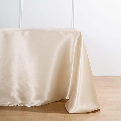 Beige satin tablecloth draping elegantly over a table edge.