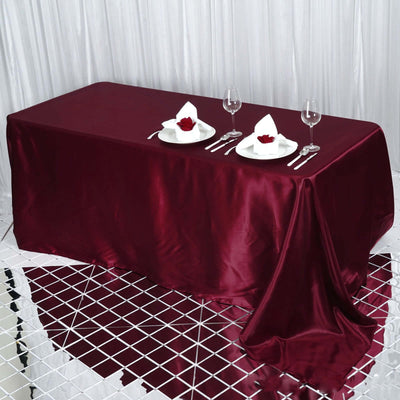 Elegant burgundy tablecloth set for dining with plates and glasses.