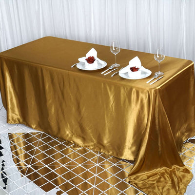 Elegant gold tablecloth draped over a table set for dining with plates and glasses.