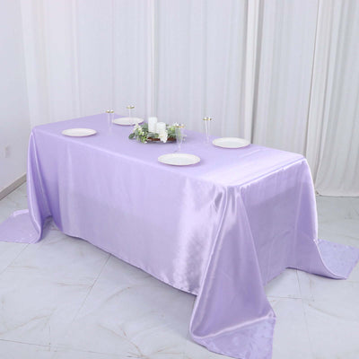 Lavender satin tablecloth draped over a table with plates and candles.