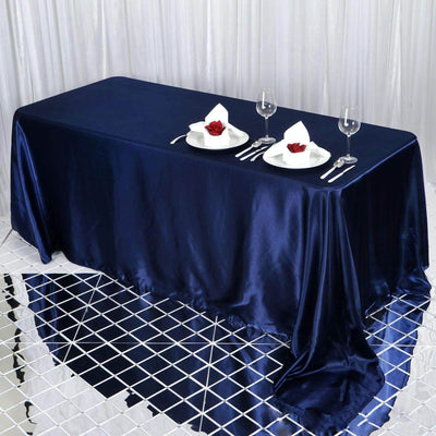 Elegant navy blue satin tablecloth draped over a dining table with settings.