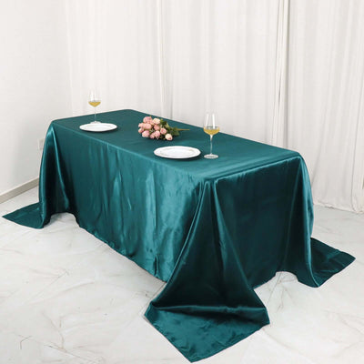 Teal satin tablecloth draped elegantly on a dining table with floral centerpiece.