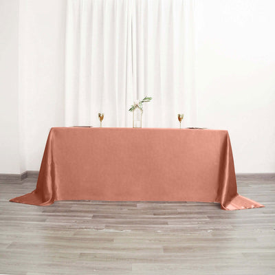 Rose satin tablecloth draped over a table in a bright, airy setting.