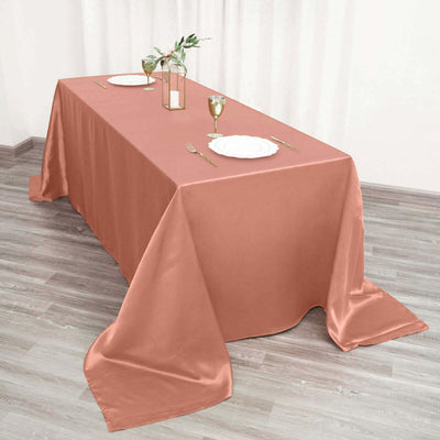 Elegant rose tablecloth draped over a dining table with plates and glassware.