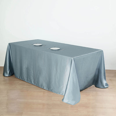 Gray satin tablecloth draped over a table with plates and cutlery.