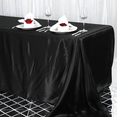 Elegant black tablecloth with white napkins and rose accents on a dining table.