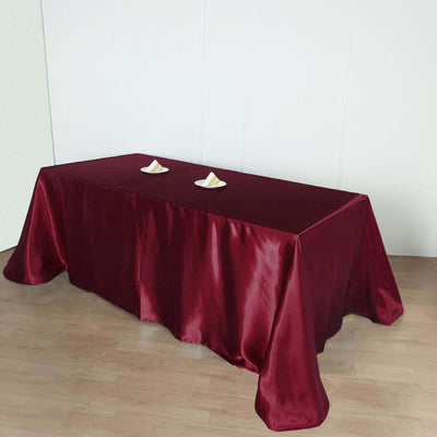 Burgundy tablecloth draped over a table with decorative items on top.
