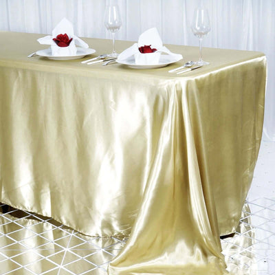 Gold satin tablecloth elegantly draping over a table set for dining.