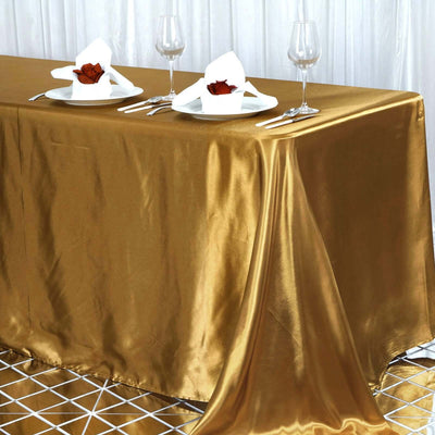 Gold satin tablecloth draped elegantly on a dining table with table settings.