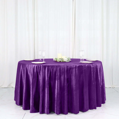 Purple tablecloth draped elegantly over a round table with decorative centerpieces.
