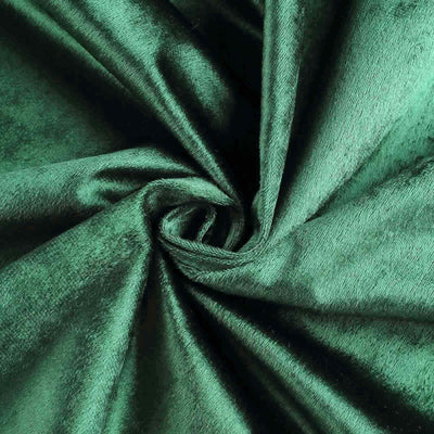Green velvet fabric texture in a swirl pattern.
