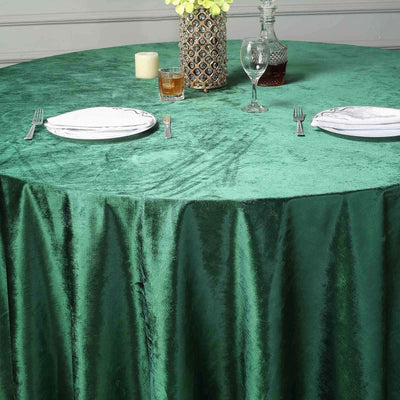 Green velvet tablecloth draped over a round table set for dining.