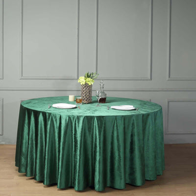 Round green tablecloth draping a table with decorative items and plates.