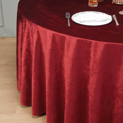 Red velvet tablecloth draping over a round table with dining setup.