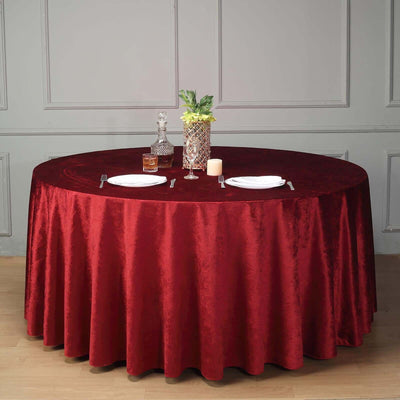 Round red tablecloth elegantly draped over a dining table with decorative items.