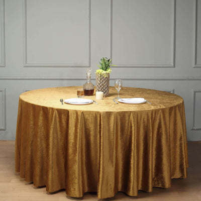 Elegant round gold tablecloth draped over a dining table with tableware.