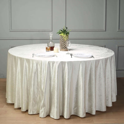 Round beige tablecloth draped over a circular table with a decorative centerpiece.