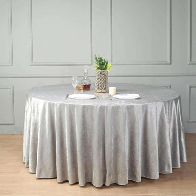 Round gray tablecloth draping over a round table set with dinnerware and decor.