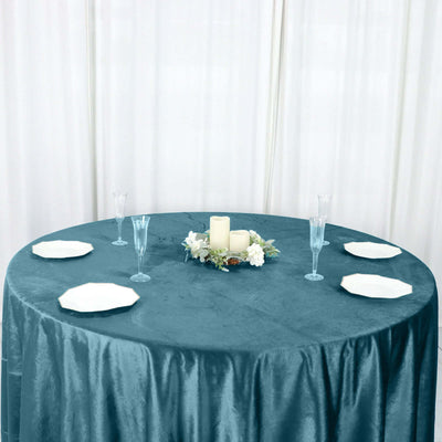 Elegant teal tablecloth set for a formal dining experience with candles and plates.