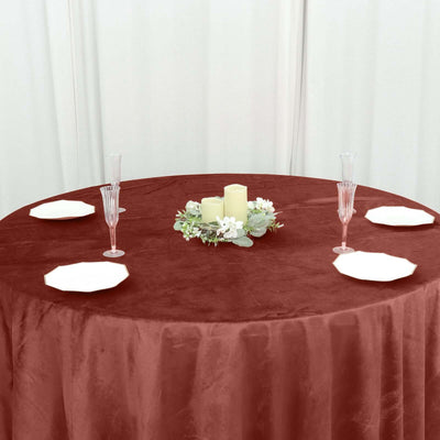 Elegant round table set with burgundy tablecloth, white plates, and centerpiece.