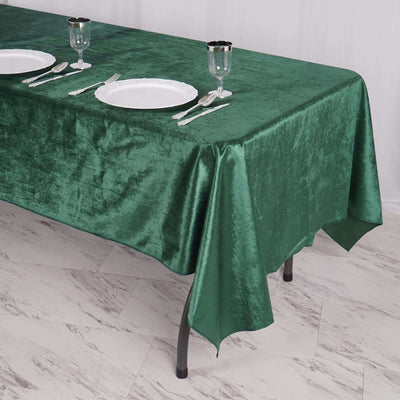 Green tablecloth draped over a dining table with plates and glassware.