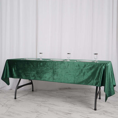 Green velvet tablecloth draped on a long table with elegant glassware.