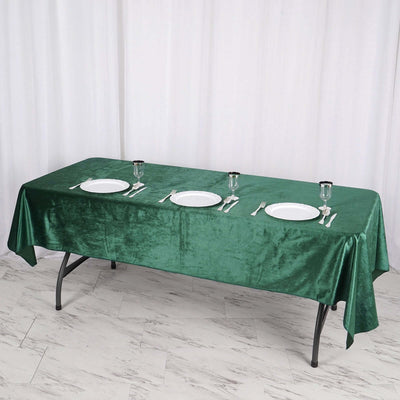 Green velvet tablecloth on a dining table set for a meal.