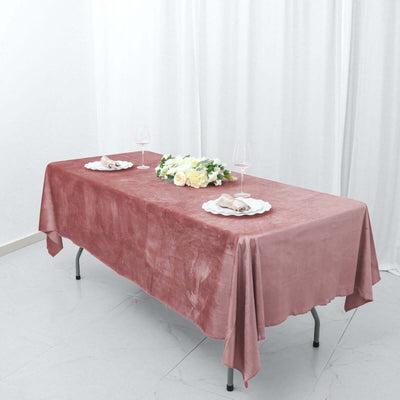 Elegant pink tablecloth draped over a table with floral centerpiece and plates.