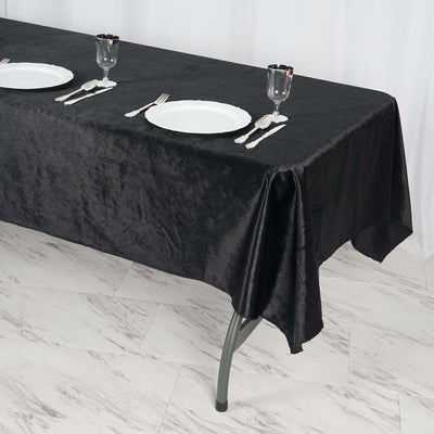 Black tablecloth draped on a table set for dining with plates and glasses.