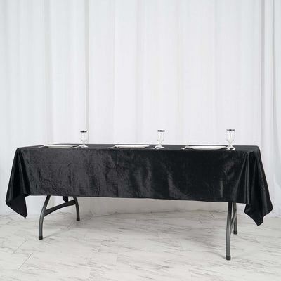 Black tablecloth draped over a table set with glasses and plates.