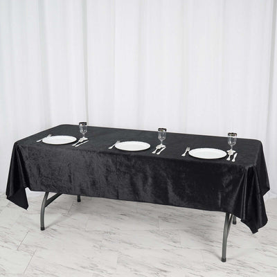 Black tablecloth draped over a table set with plates and glasses.