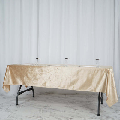 Elegant gold tablecloth draped over a table with glassware on a neutral backdrop.