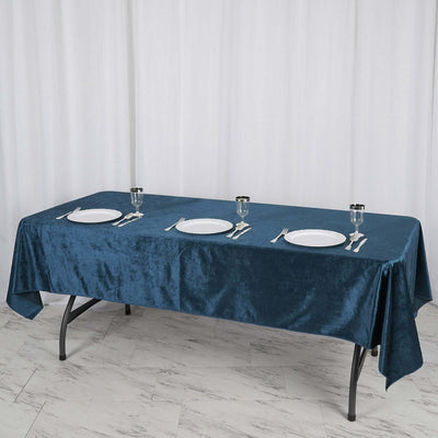Blue tablecloth on a dining table set with plates and glasses.