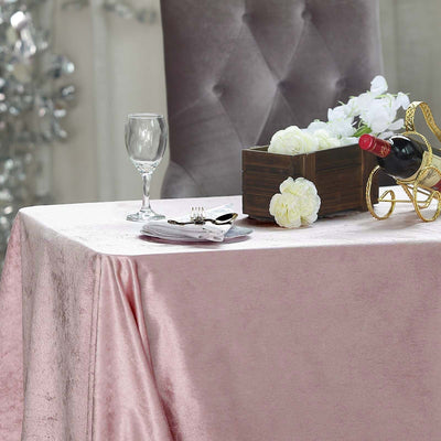 Elegant table setting with wine, glass, and decorative flowers on a pink tablecloth.