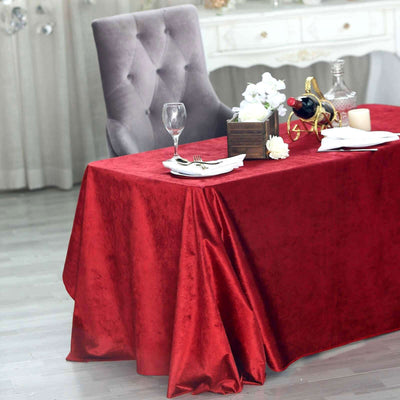 Red velvet tablecloth draped elegantly on a dining table with decor.