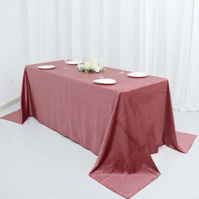 Elegant rose table linen draped over a rectangular table with plates and glasses.