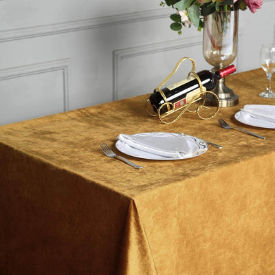 Elegant gold tablecloth styled with wine and tableware for dining setup.