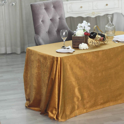 Elegant gold tablecloth draped over a table set with wine and flowers.
