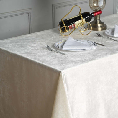 Elegant cream tablecloth set for dining with wine and decorative plate.