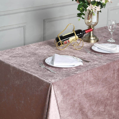 Elegant rose gold tablecloth on a dining table set with plates and wine.