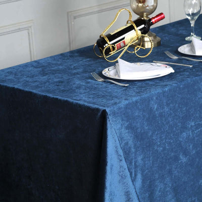 Navy blue velvet tablecloth on a dining table with wine and plates.