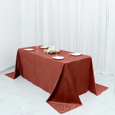 Elegant red tablecloth draped over a dining table with plates and candles.