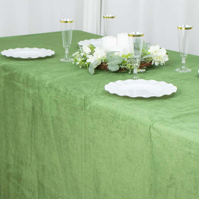 Green tablecloth with white plates and decorative candles.