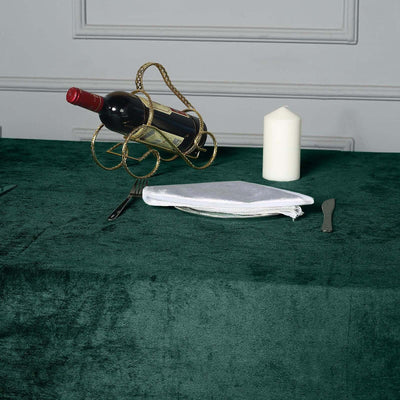 Elegant dining setup with wine, candle, and tableware on a green tablecloth.