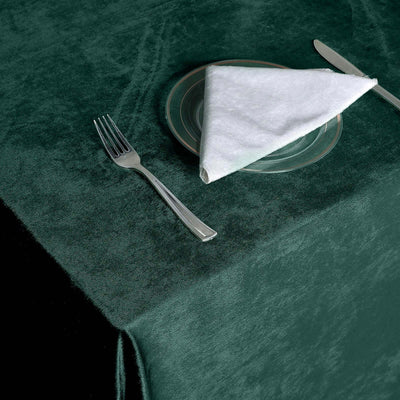 Dark green tablecloth with fork, knife, and folded napkin set for dining.