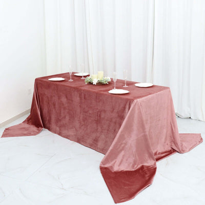 Elegant rose tablecloth draped on a table with plates and decorations.